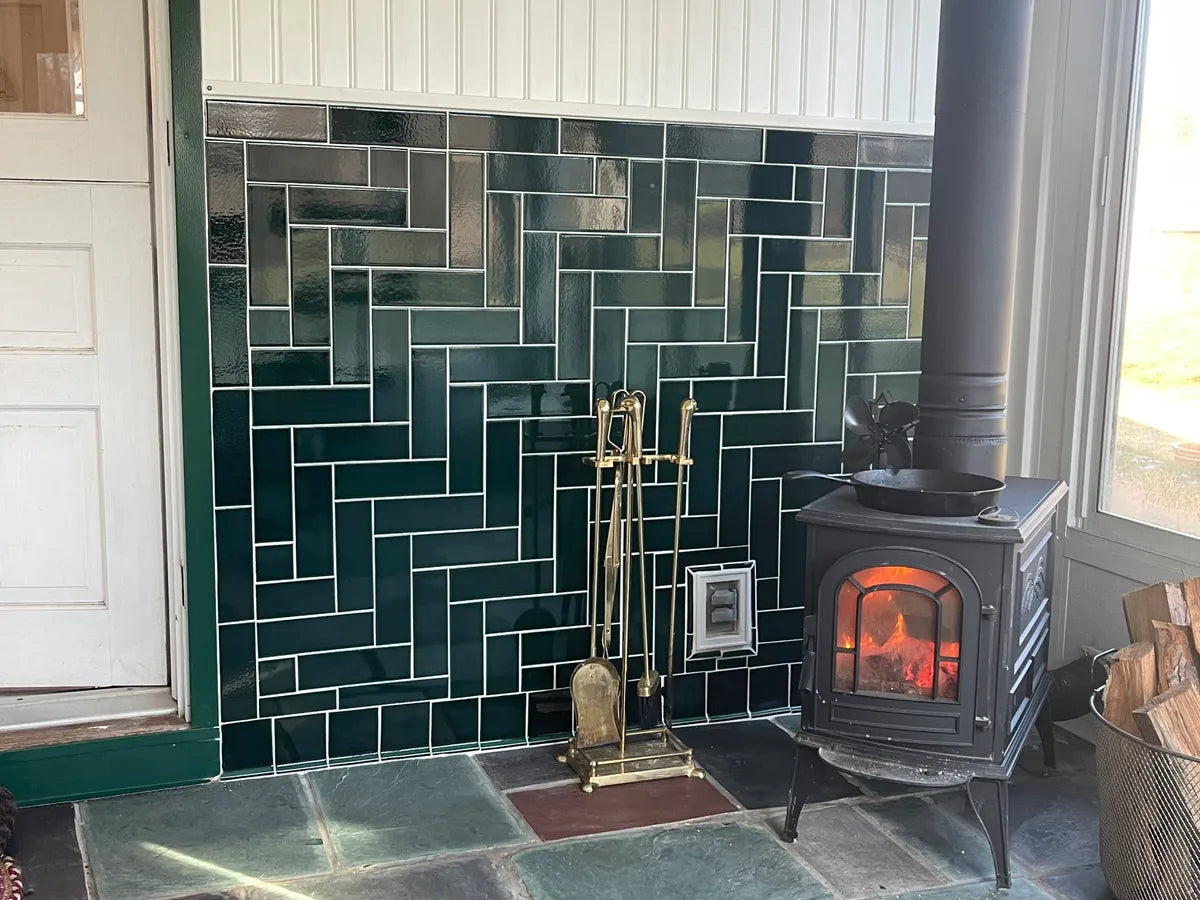 2022 stephen miano rights lo res FC577098 ceramic 3x9 herringbone woodstove fireplace surround accent wall 4x4 cove base trim evergreen 3
