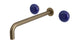 Foundry Two Handle Wall Mount 12" Lavatory Faucet with Pebble Ceramic Knob Handles in Antique Brass